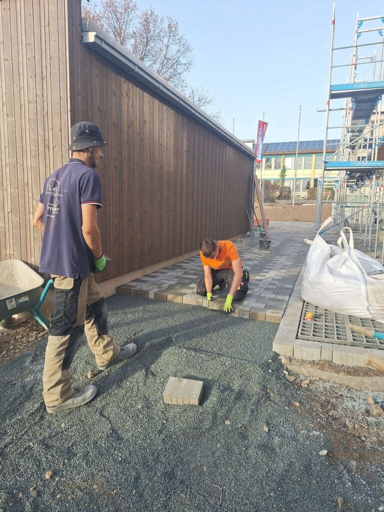 Zwei Mitarbeiter von Weißmüller Garten & Landschaftsbau beim Pflastern