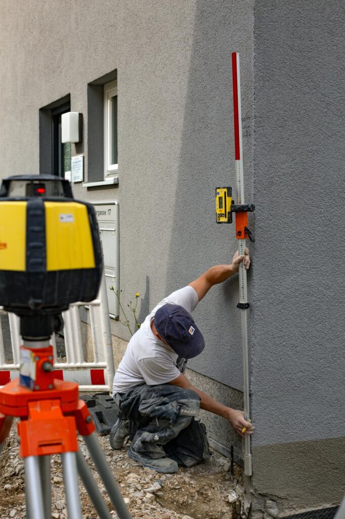 Mitarbeiter von Weißmüller Garten & Landschaftsbau bei der Vermessung einer Hauswand